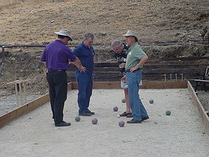 Four bocce players standing around a jack whil...