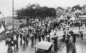 English: Brass band leads a parade along the w...